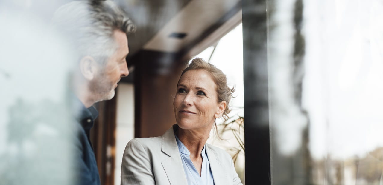 Smiling businesswoman with businessman in cafe seen through glass