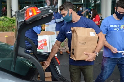 A Raymond James associate unloads food from car