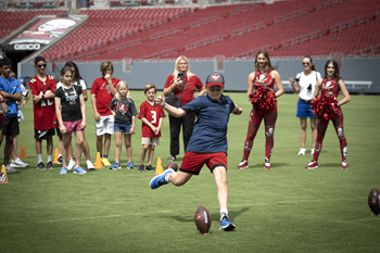 A young boy winds up to kick a football
