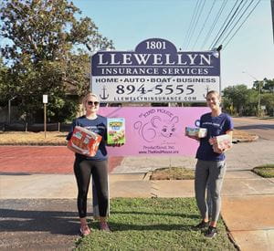 Associates pose in front of The Kind Mouse sign with donated food