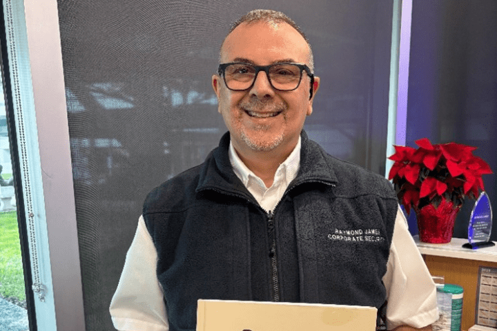 photo of Sergio Faccio holding a book titled "Sergio's Seven: Wisdom at the Door"